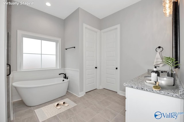 bathroom with double vanity, a soaking tub, tile patterned flooring, and recessed lighting