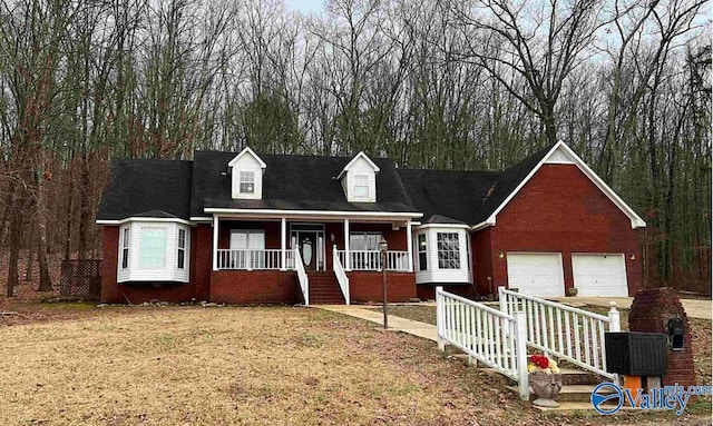 new england style home with a garage, a porch, and a front yard