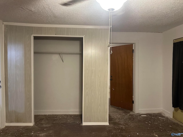 unfurnished bedroom featuring ceiling fan, a textured ceiling, wooden walls, and a closet