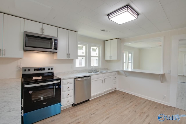 kitchen featuring light wood-type flooring, stainless steel appliances, a sink, visible vents, and white cabinets