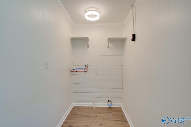 laundry area with baseboards, crown molding, wood finished floors, and wood walls