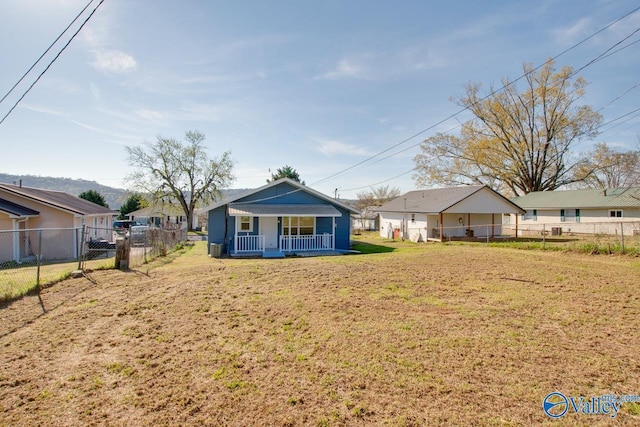 view of front of home with covered porch, a front yard, and fence