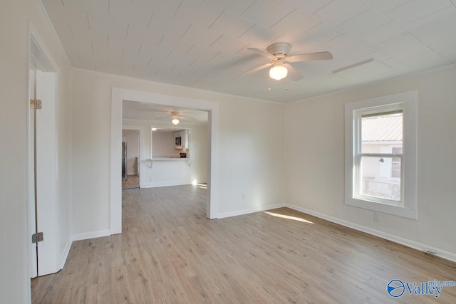 empty room with a ceiling fan, ornamental molding, baseboards, and light wood finished floors