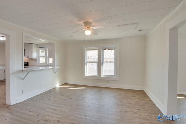 unfurnished living room with baseboards, a ceiling fan, crown molding, and light wood-type flooring