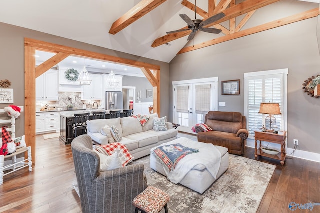 living room featuring high vaulted ceiling, french doors, hardwood / wood-style flooring, ceiling fan, and beam ceiling