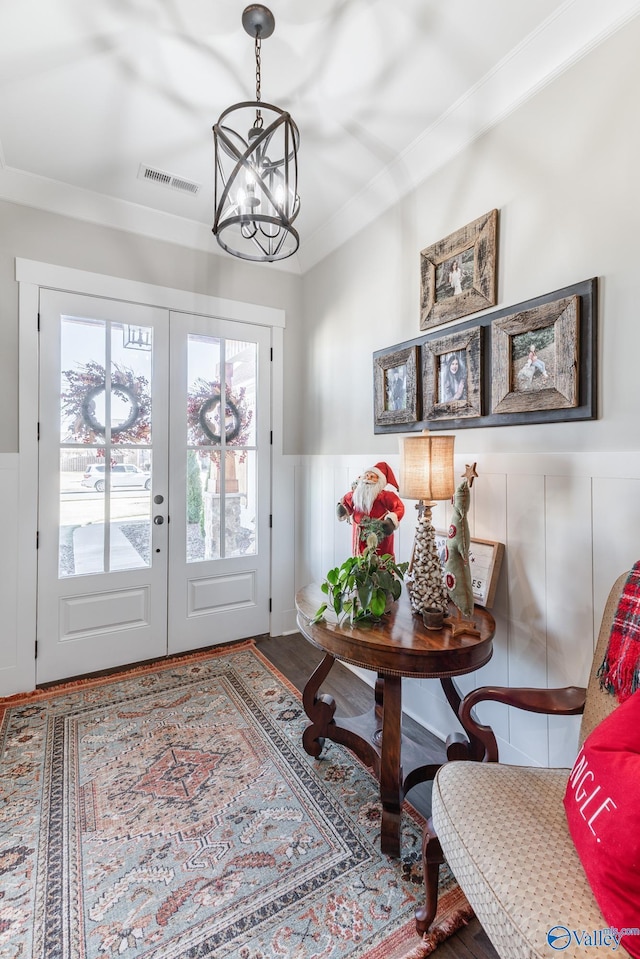 foyer featuring a chandelier, french doors, hardwood / wood-style floors, and ornamental molding