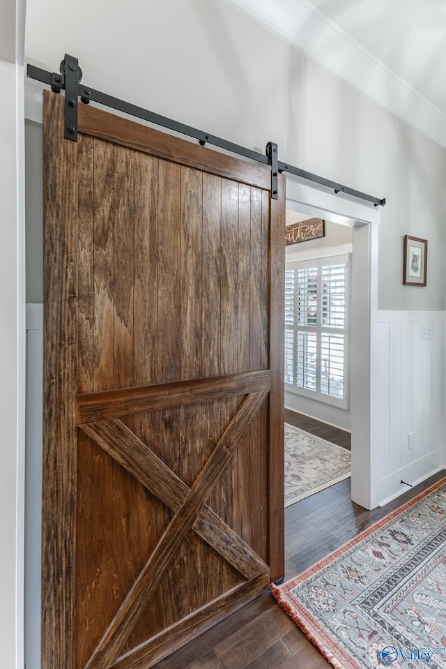 interior details with a barn door, wood-type flooring, and ornamental molding