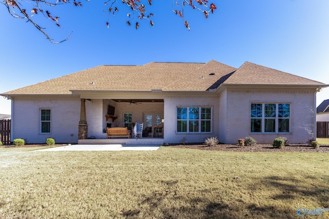 rear view of property featuring ceiling fan, a patio area, and a lawn