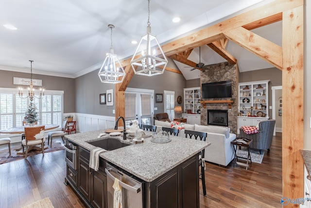 kitchen with a breakfast bar, dark brown cabinets, a stone fireplace, and pendant lighting