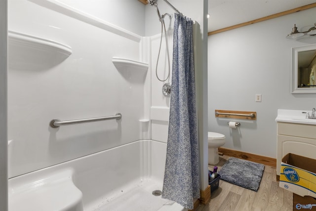 bathroom with vanity, wood finished floors, toilet, baseboards, and a shower stall