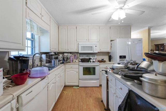 kitchen with a sink, white cabinets, white appliances, and light countertops