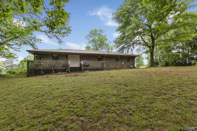 back of house featuring a lawn, a wooden deck, and brick siding