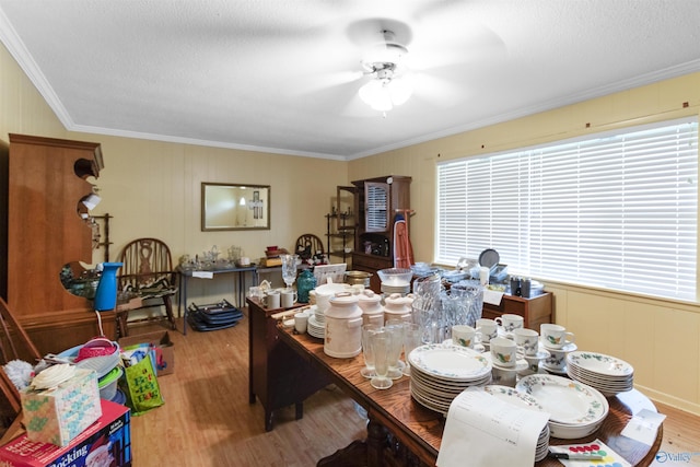 dining space with a decorative wall, ornamental molding, a ceiling fan, and wood finished floors