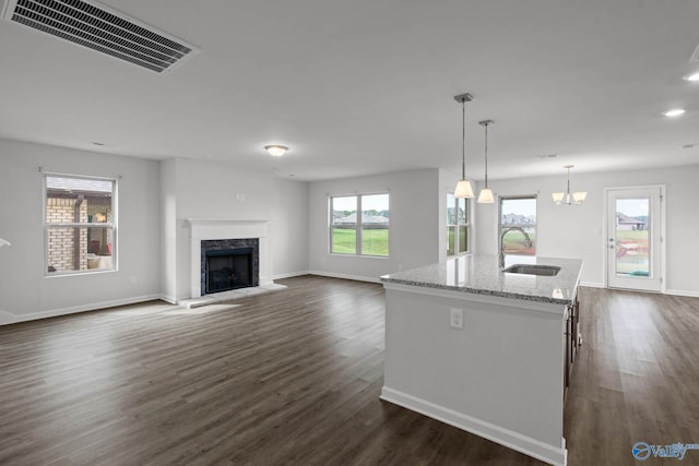 kitchen featuring plenty of natural light, dark hardwood / wood-style floors, sink, an island with sink, and hanging light fixtures