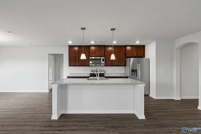 kitchen with a kitchen island with sink, appliances with stainless steel finishes, decorative light fixtures, and dark hardwood / wood-style flooring