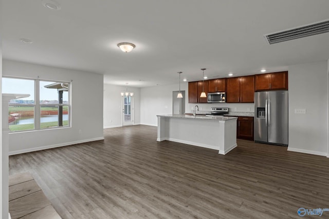 kitchen featuring appliances with stainless steel finishes, decorative light fixtures, a center island with sink, dark hardwood / wood-style floors, and sink