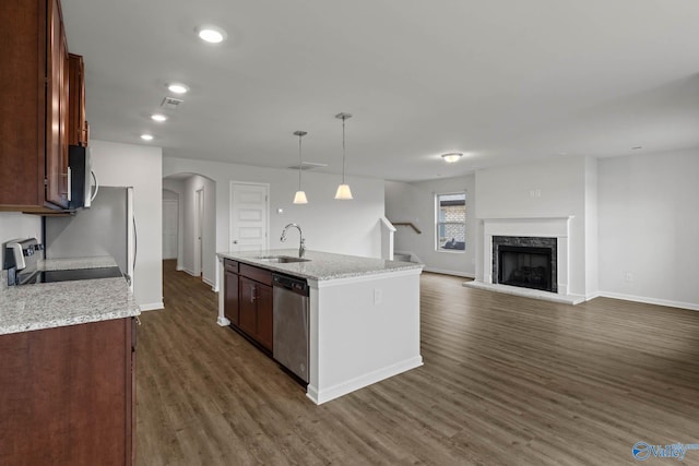 kitchen with appliances with stainless steel finishes, hanging light fixtures, an island with sink, dark hardwood / wood-style floors, and sink