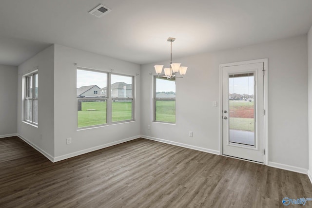 unfurnished dining area featuring an inviting chandelier, wood-type flooring, and plenty of natural light