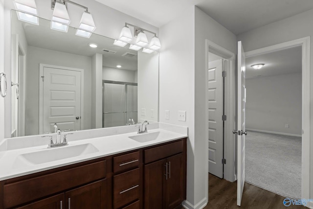 bathroom with hardwood / wood-style flooring, a shower with door, and vanity