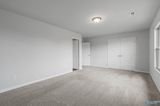 unfurnished bedroom featuring multiple windows, carpet, and a closet