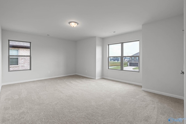 unfurnished room featuring light colored carpet and plenty of natural light