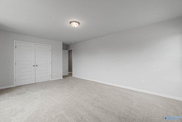 unfurnished bedroom featuring light colored carpet and a closet