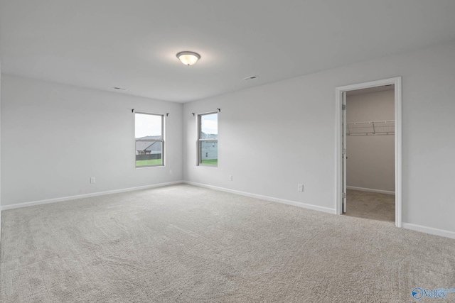 unfurnished bedroom with light carpet, a walk in closet, and a closet