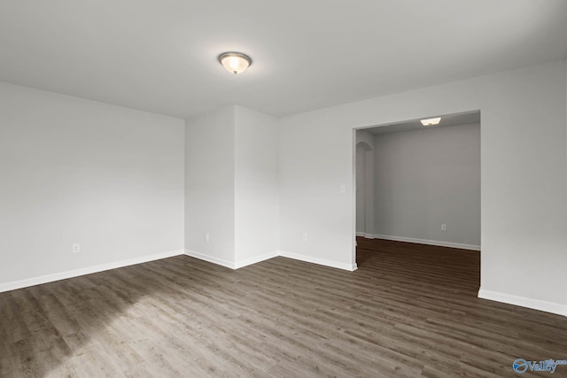 unfurnished room with dark wood-type flooring