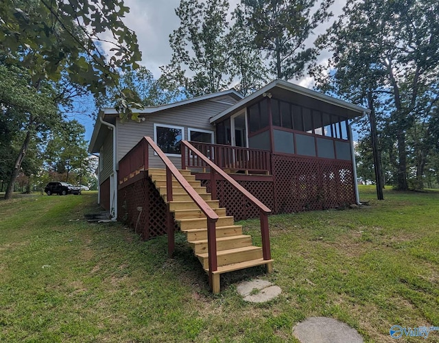 back of house featuring a yard, a sunroom, and a wooden deck