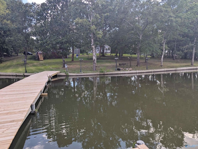 view of dock with a water view and a lawn