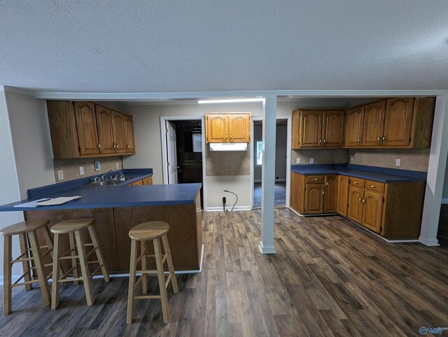 kitchen featuring a kitchen breakfast bar, a textured ceiling, and dark hardwood / wood-style floors