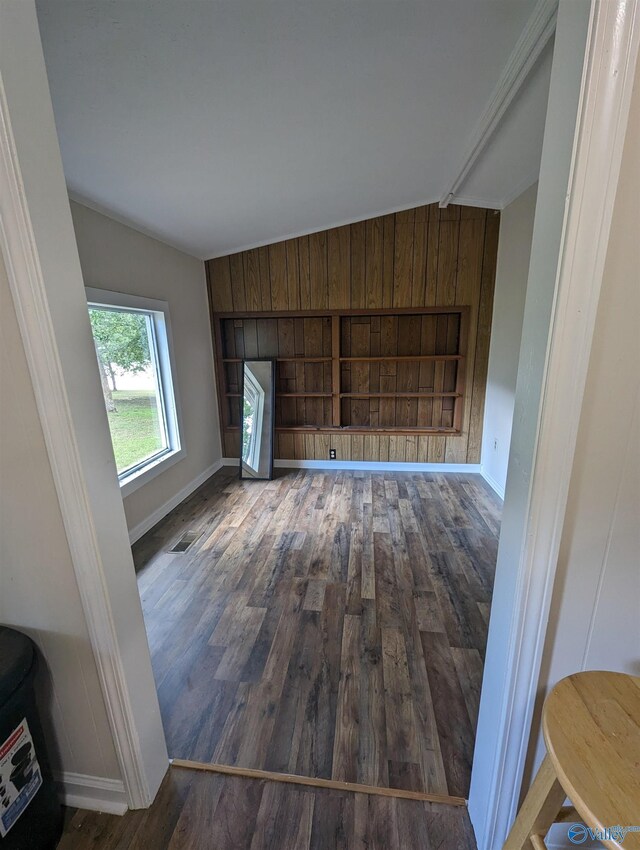 unfurnished living room featuring wood walls, lofted ceiling, and hardwood / wood-style flooring