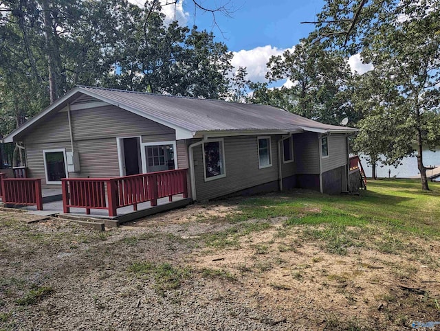 back of property featuring a deck, metal roof, and a yard