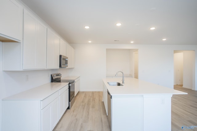 kitchen featuring light hardwood / wood-style flooring, stainless steel appliances, an island with sink, white cabinetry, and sink