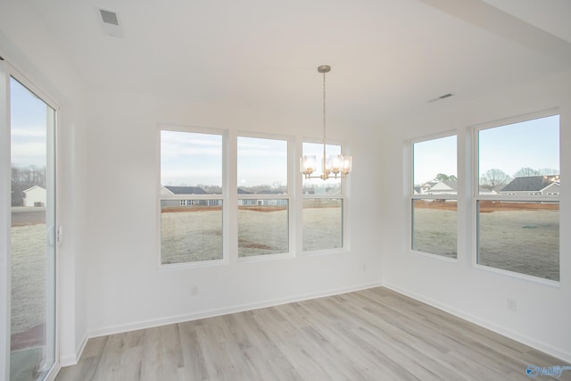 unfurnished dining area with light hardwood / wood-style floors, a notable chandelier, and plenty of natural light