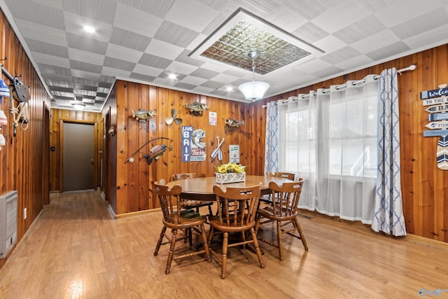 dining room with light hardwood / wood-style flooring and wooden walls