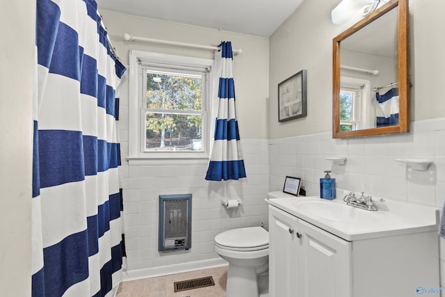 bathroom featuring tile patterned flooring, heating unit, a wealth of natural light, and tile walls