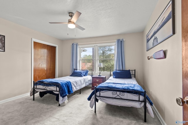 bedroom with ceiling fan, light carpet, and a textured ceiling