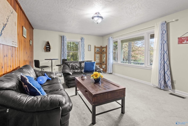 living room featuring wood walls, light carpet, and a textured ceiling