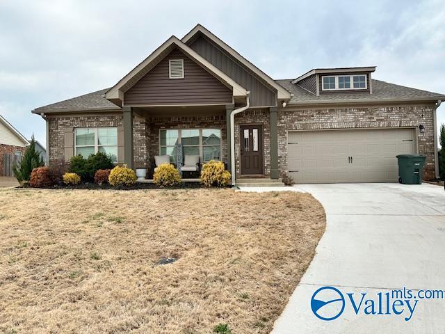 craftsman house with concrete driveway, an attached garage, brick siding, and a front yard