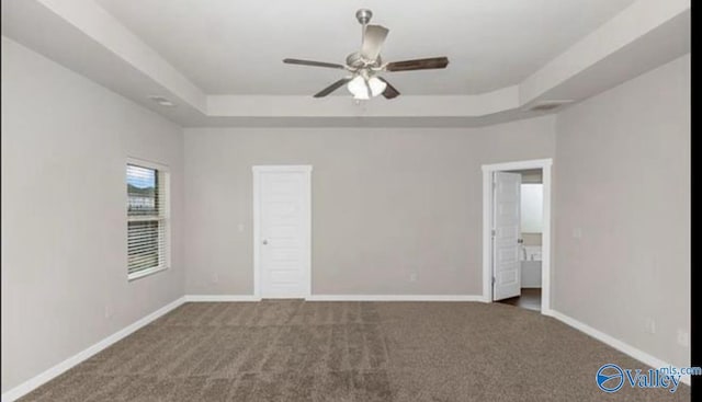 unfurnished bedroom with a tray ceiling, baseboards, and carpet floors