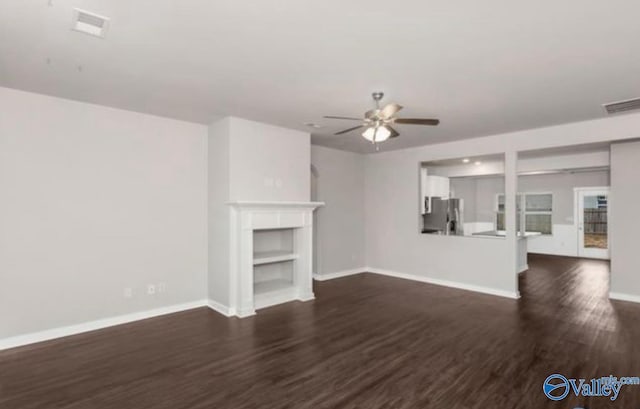 unfurnished living room with a fireplace, visible vents, dark wood-style flooring, and baseboards