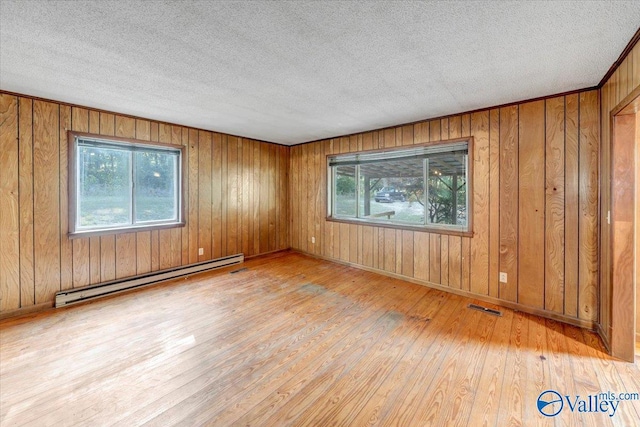 empty room with a baseboard radiator, a textured ceiling, and light hardwood / wood-style floors