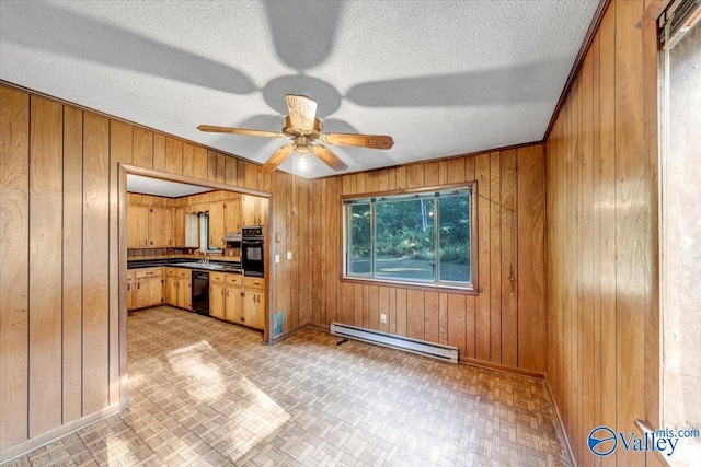 kitchen featuring ceiling fan, a baseboard radiator, wood walls, and black appliances