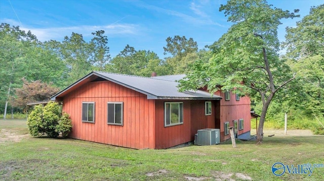 view of property exterior with central AC unit and a yard