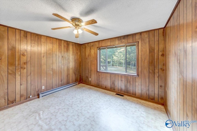 empty room featuring ceiling fan, a baseboard radiator, wooden walls, and a textured ceiling