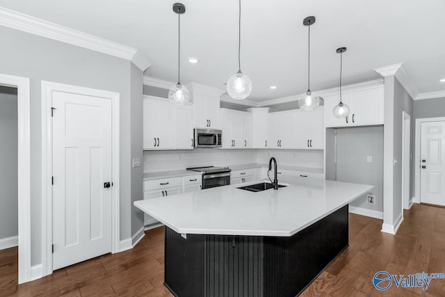 kitchen with a sink, dark wood finished floors, stainless steel appliances, white cabinets, and ornamental molding