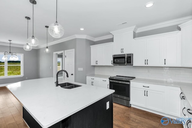 kitchen with light countertops, crown molding, appliances with stainless steel finishes, an island with sink, and a sink