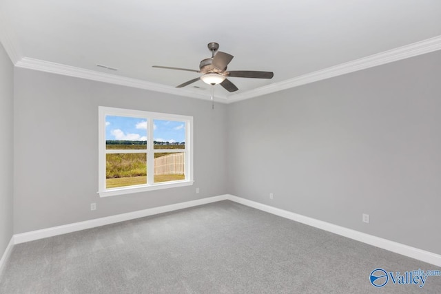 carpeted spare room featuring baseboards, ornamental molding, visible vents, and ceiling fan