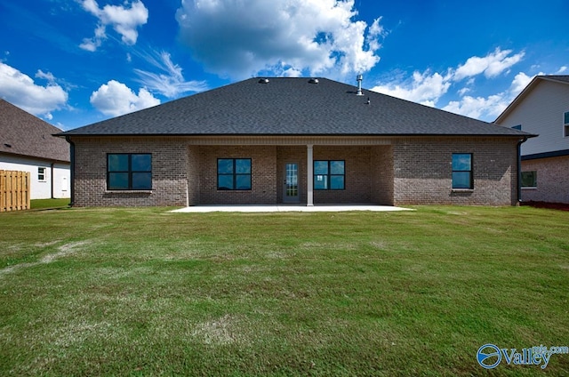 back of property featuring a lawn, brick siding, a shingled roof, and a patio area